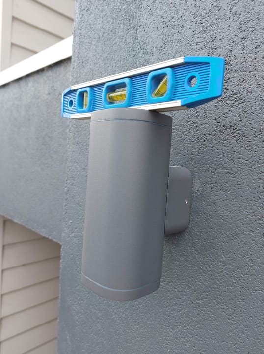 Exterior wall light going on straight — spirit level across the fitting before the screws bite.
