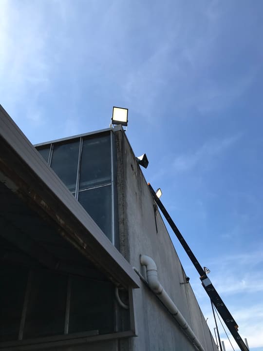 Floodlight mounted high on the building line for security and after-dark access.