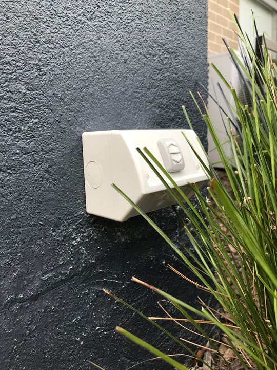 Weatherproof outdoor power point on a rendered wall — sealed and rated for the weather.